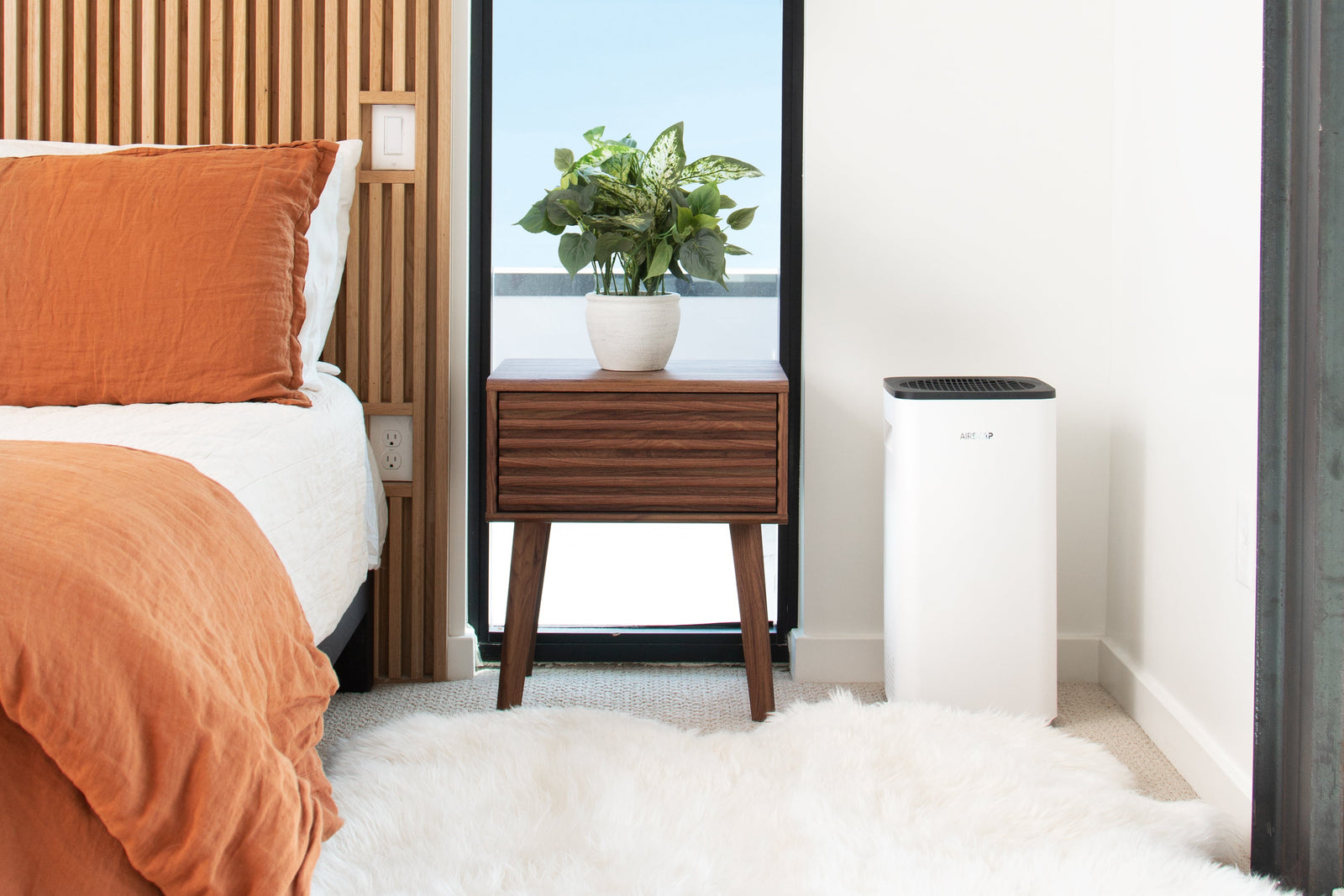 AirSoap air purifier running in a sunlit bedroom where household dust and dust mites collect