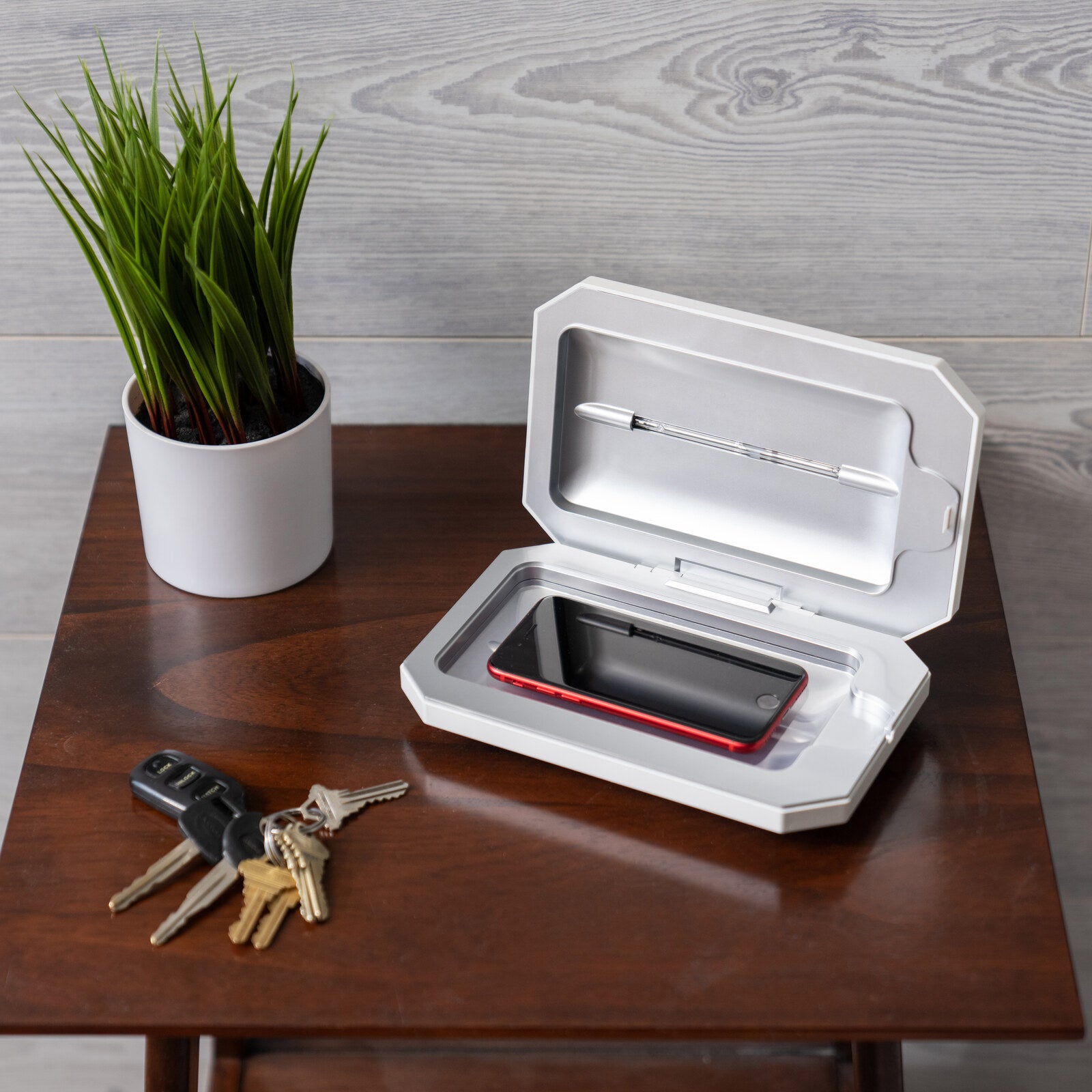 PhoneSoap Basic open on a table with a phone inside and a cable pass-through slot