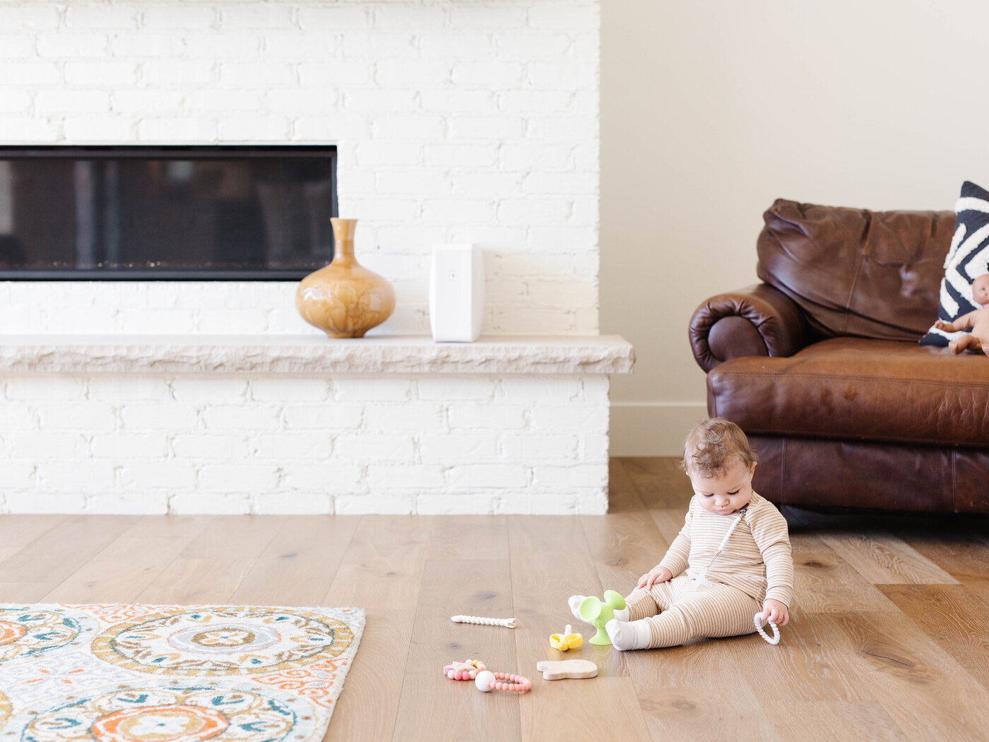 A baby playing with toys on the floor with HomeSoap on the mantel