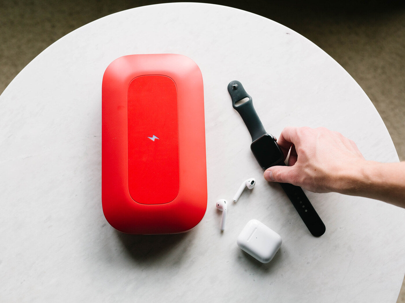 PhoneSoap Pro on a table beside a smartwatch and earbuds ready to sanitize