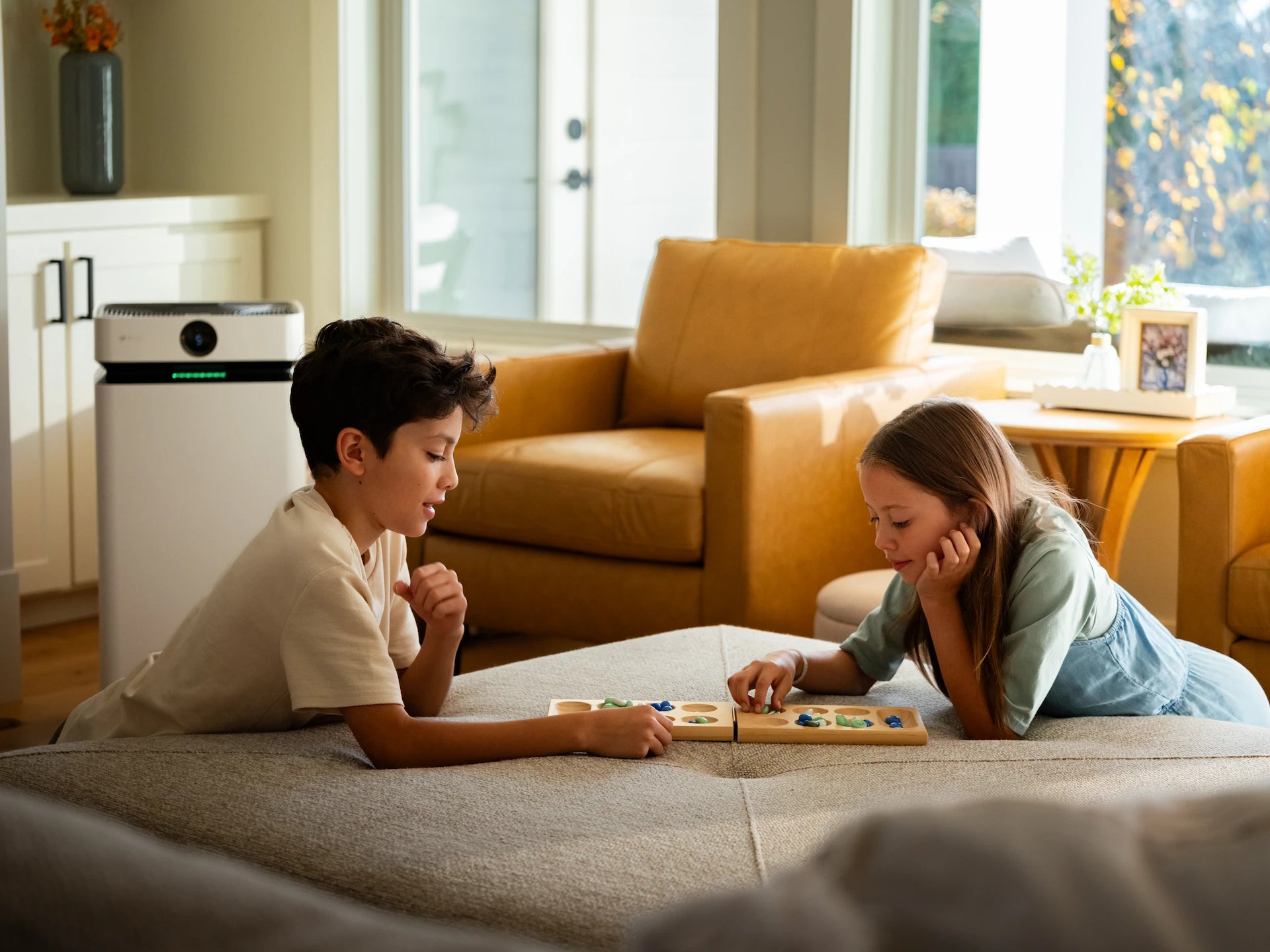 Two children playing a board game in a living room with the AirSoap X8 behind them