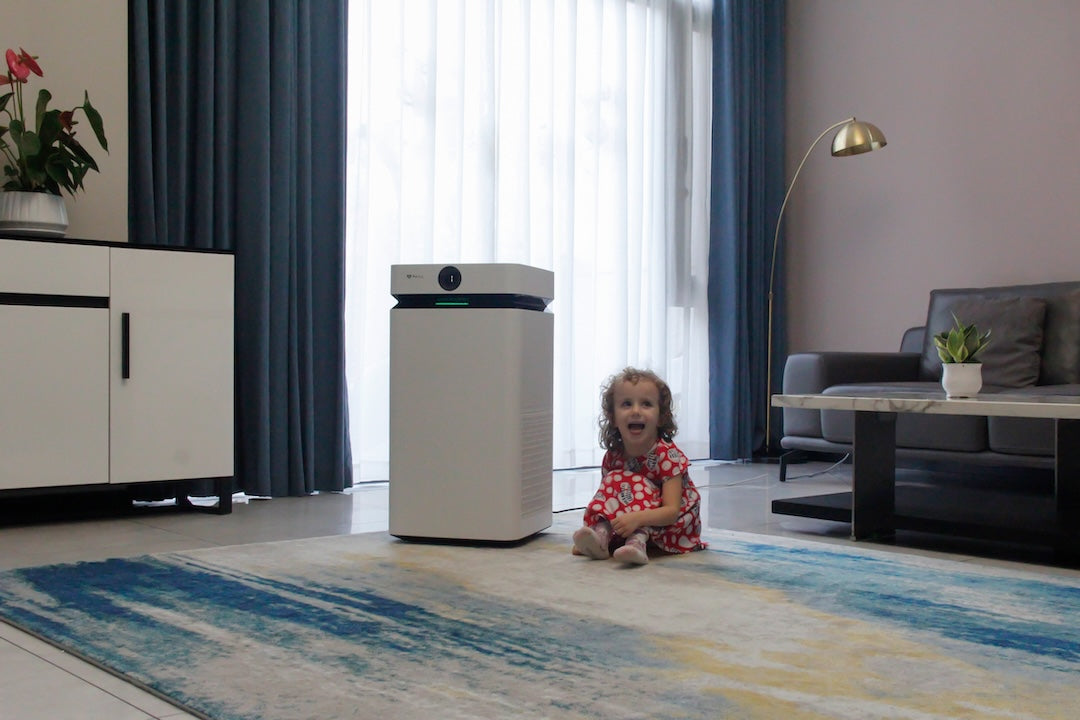 A bright living room with a small child playing and the AirSoap X8 standing at the centre of the room